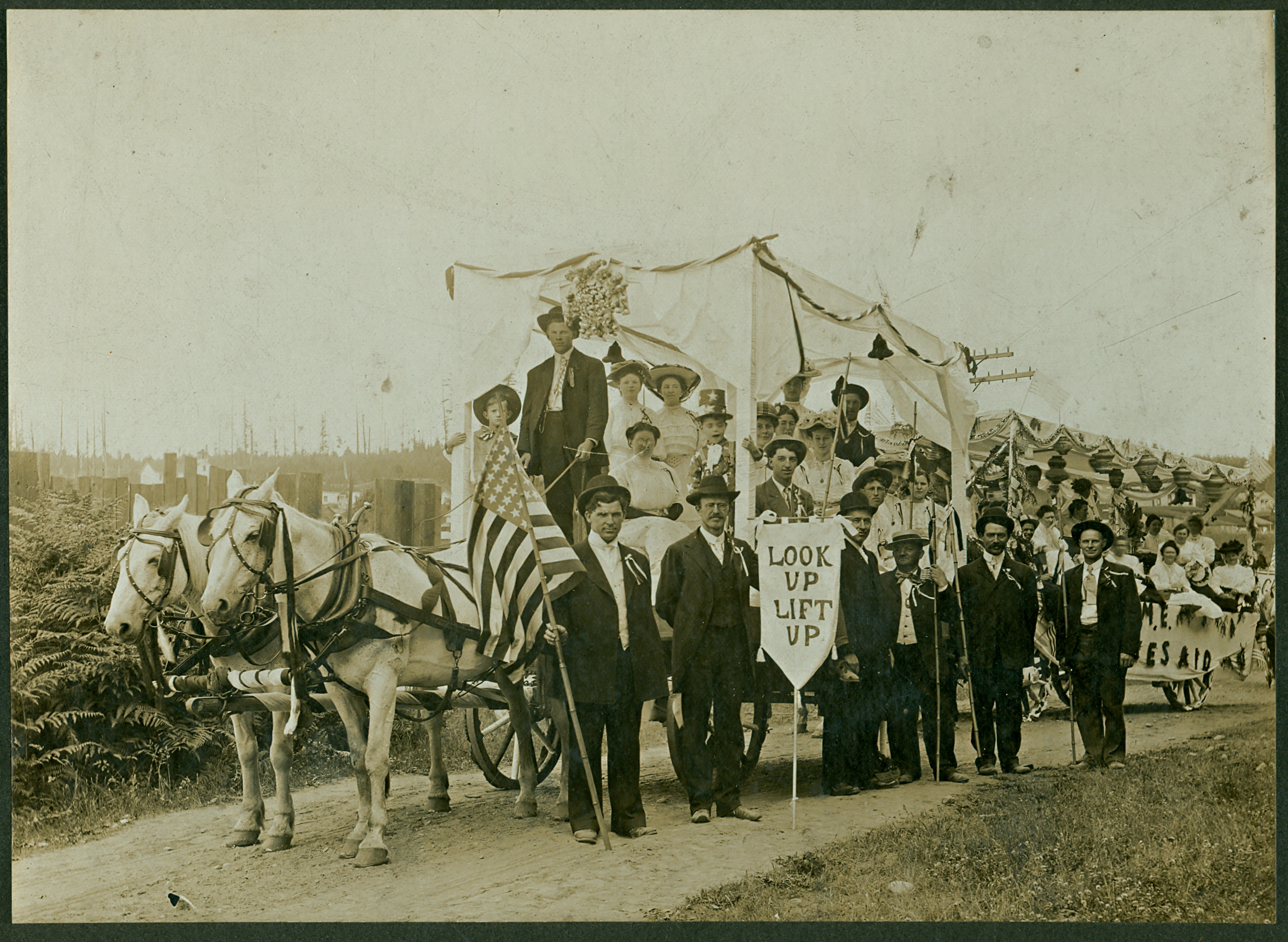 The Methodist Church float in the 1908 Bothell 4th of July Parade. The caption on the back of the picture identifies some of the participants. The driver/teamster is Howard Hosmer. Seated behind him is Lena Bothell. Standing behind her is Bertha Dutton. Clark Ross is standing just above the sign "Look Up Lift Up." 