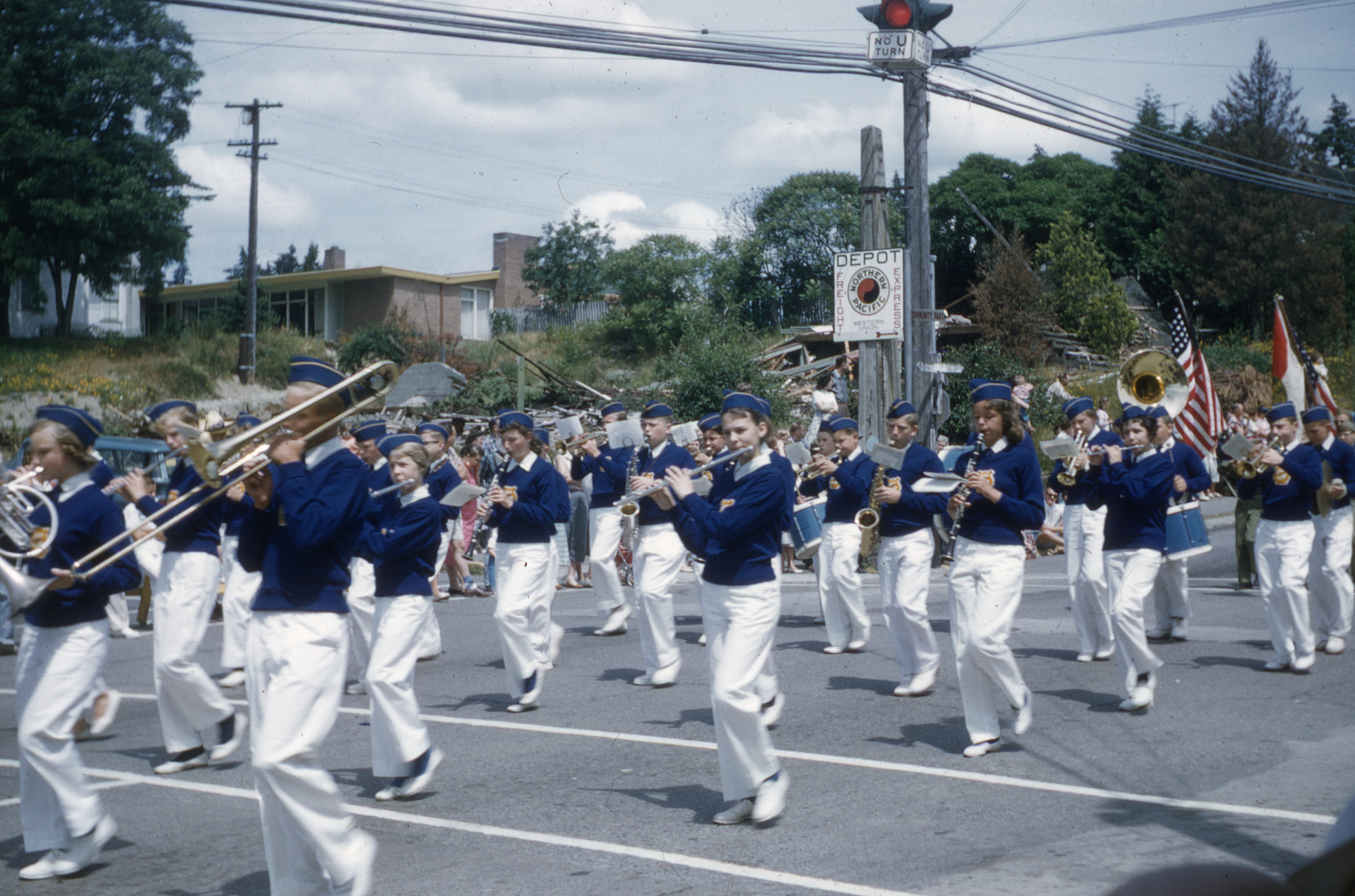 The W. A. Anderson Junior High School marching band in the 1959 Bothell 4th of July parade, at the corner of Main St. and 2nd St. (now 102nd Avenue NE). The debris behind them is the demolished structure of the Methodist Church that stood there from 1890 until 1958, when a new church building opened on West Hill. (It is possible that this picture is from the 1958 parade--there is disagreement. If it could be determined when the bank building went up on the old church site, the date could be better established.)