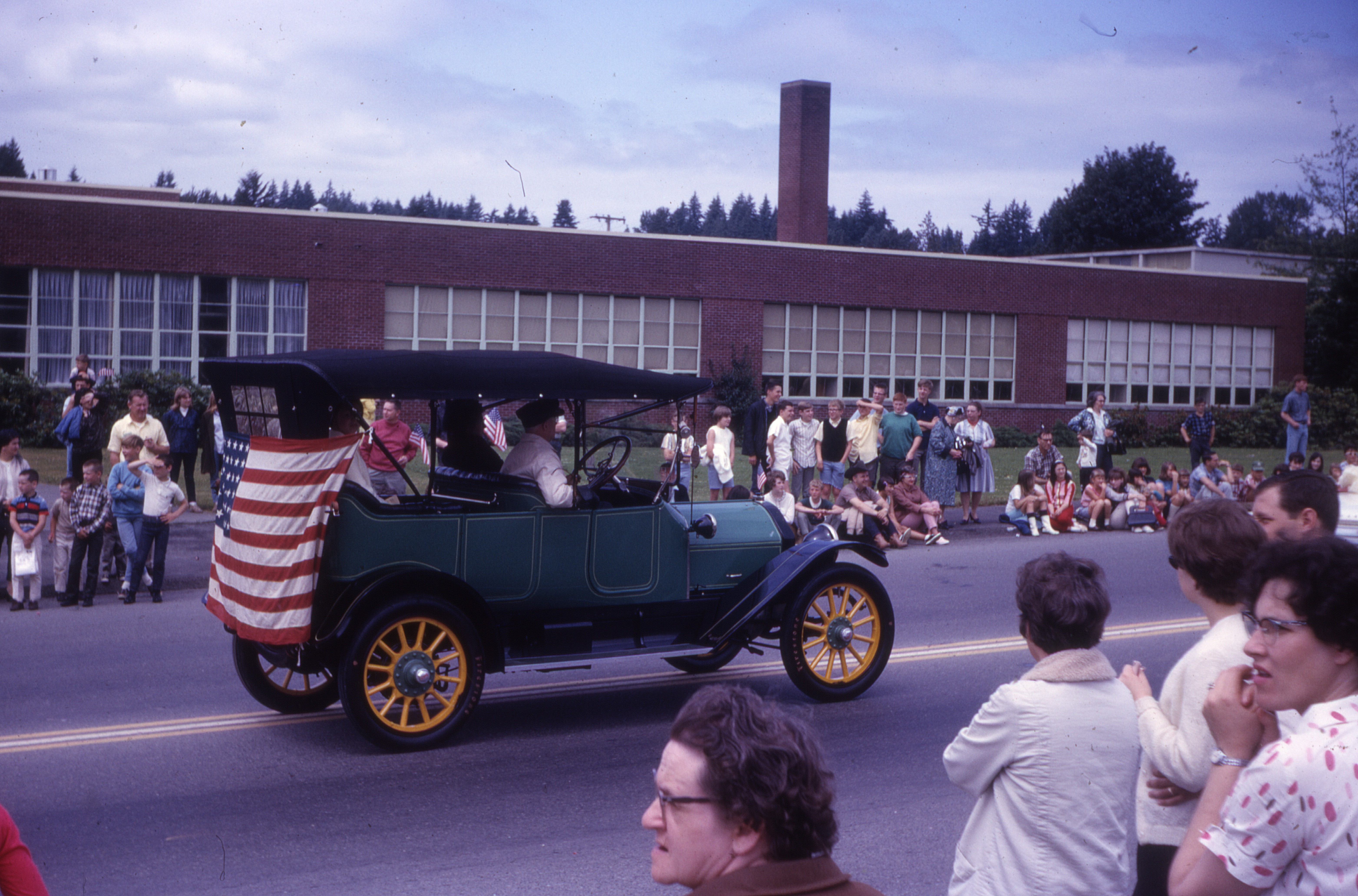 A vintage sedan, one of many Horseless Carriages in the 1966 parade, drives past Ricketts Elementary School. The school's name honored a long-time community dentist and member of the Northshore District school board , Dr. G. E. Ricketts.